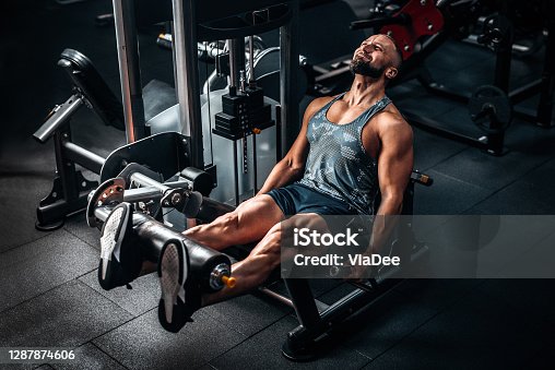 muscular man using weights machine for legs at the gym. hard training