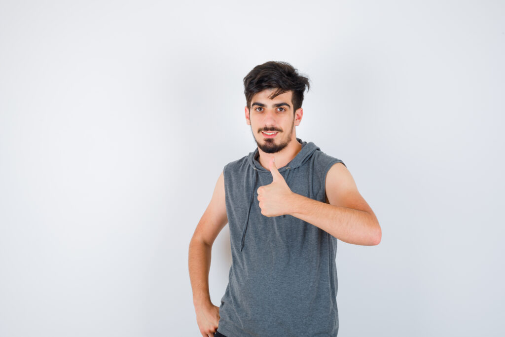 Young Man Showing Thumb Up While Holding Hand Waist Gray T Shirt Looking Serious 1024x683