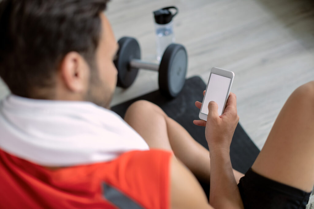 close up of sportsman text messaging on mobile phone in a gym.