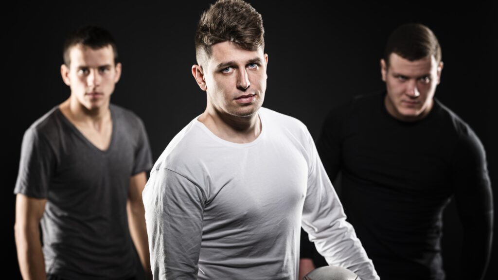 front view three male rugby players posing with ball