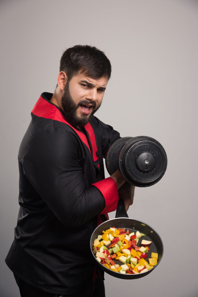 young man holding a dumbbell and pan with vegetables